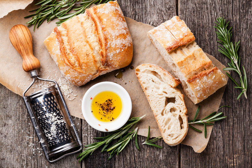 osteoporosis and gluten sensitivity - sliced bread ciabatta and extra virgin olive oil on wooden background