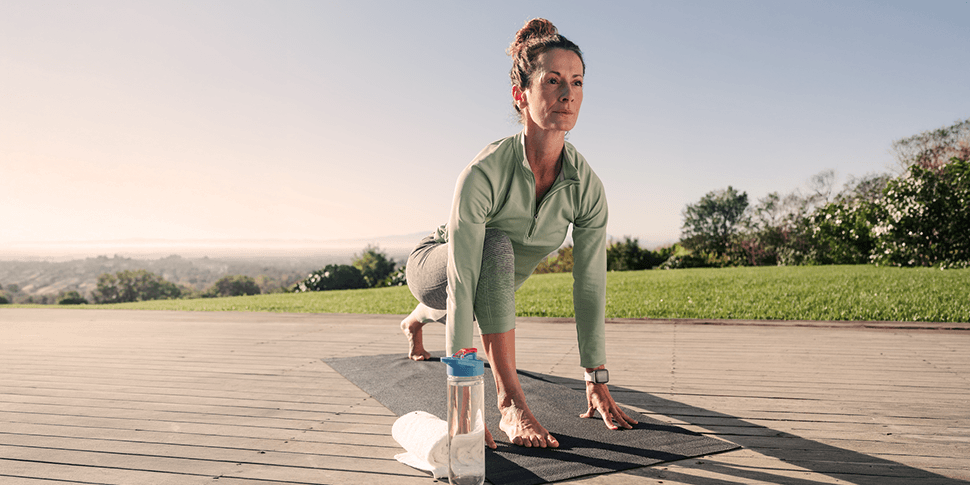 A woman confidently performing a deep lunge stretch outdoors