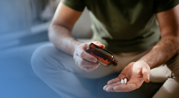 Man pouring out supplement pills