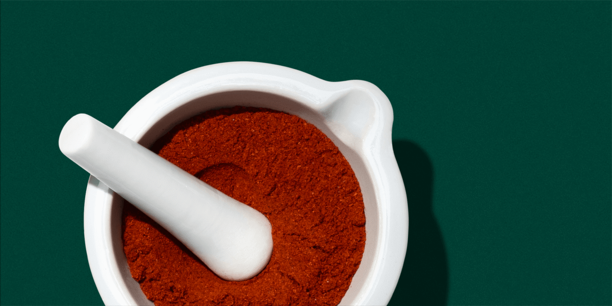 Top-down view of red AstaReal astaxanthin powder inside a white ceramic mortar and pestle