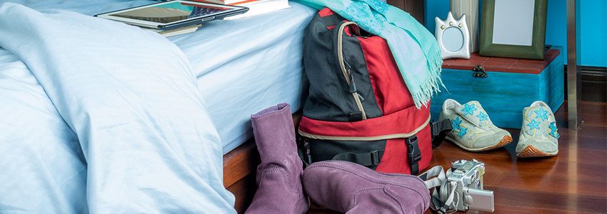 Backpack, camera, and shoes next to bed