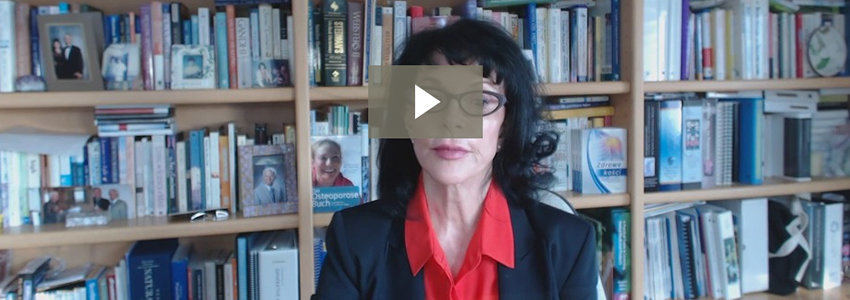 Lara Pizzorno in red shirt and blazer in front of bookshelf